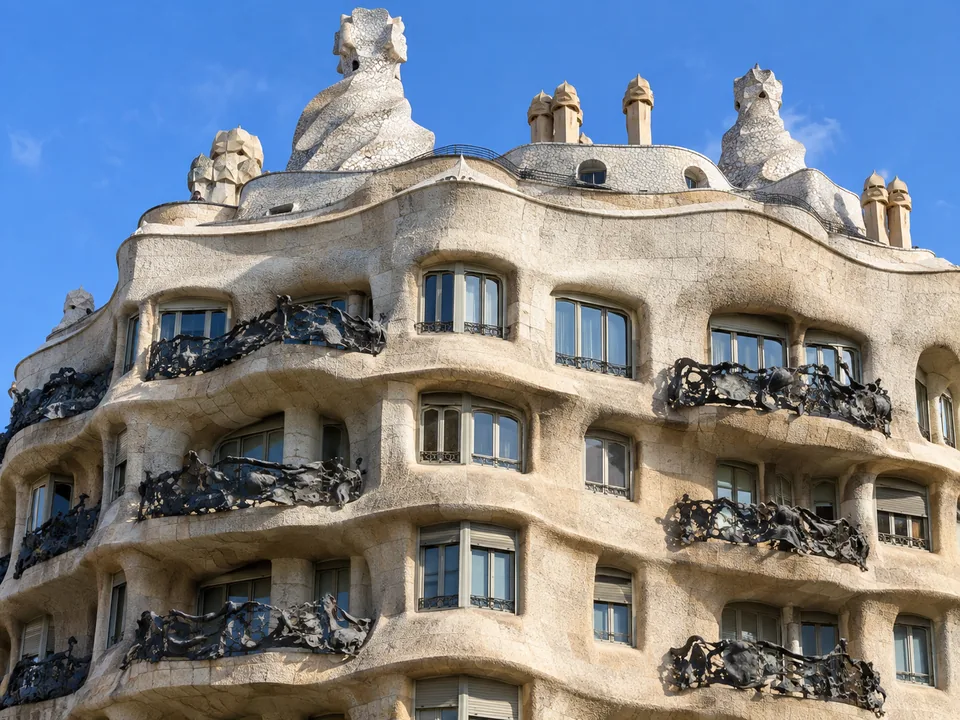 Dark wrought-iron balcony railings like tangled seaweed over a rippling cream stone facade