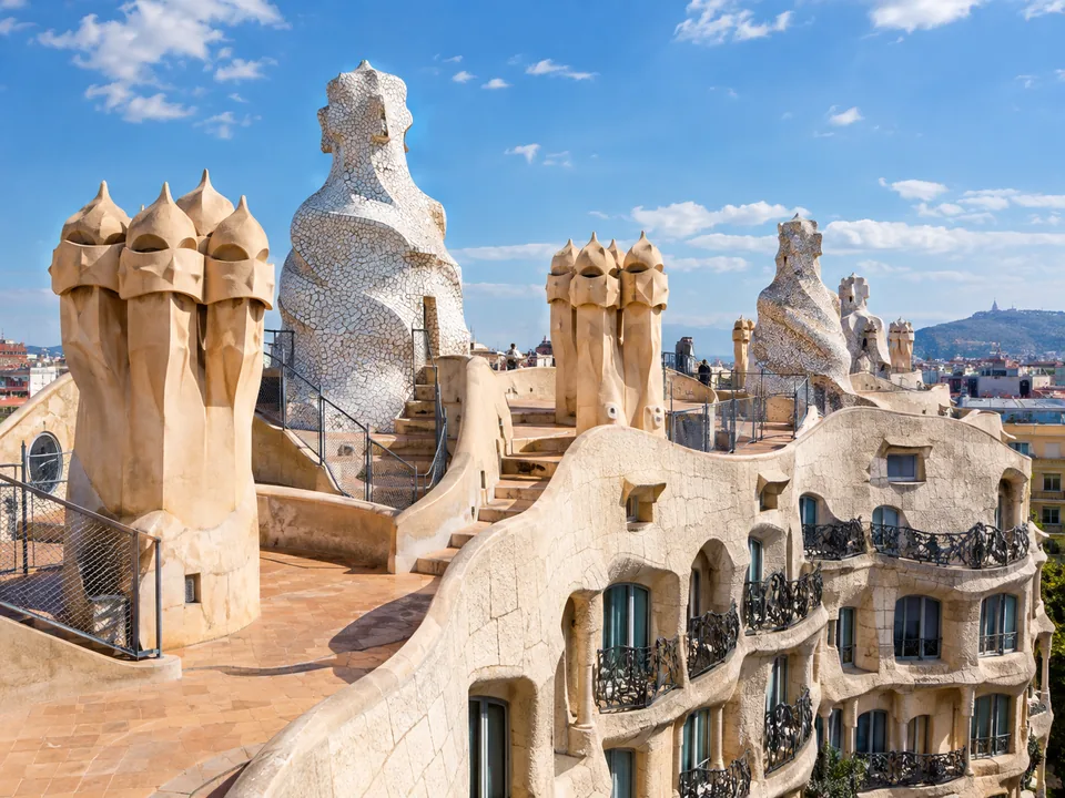 Undulating stone steps and walkways between cream chimneys on a rooftop under a blue sky