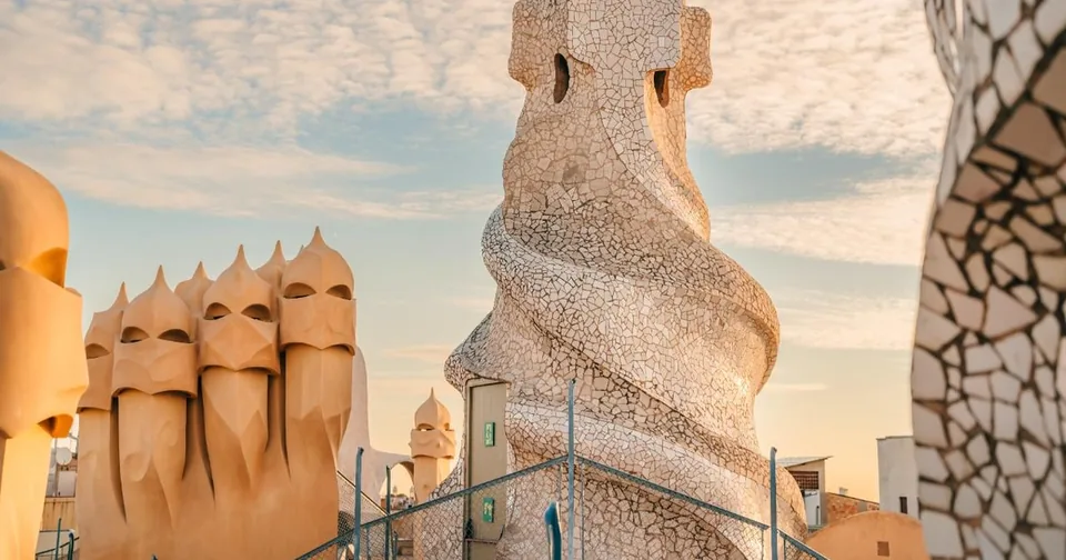Twisted cream rooftop chimneys and a mosaic-clad tower against a pale sky