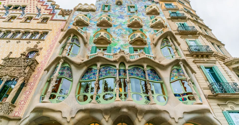 A facade covered in blue and green mosaic with bone-like window columns