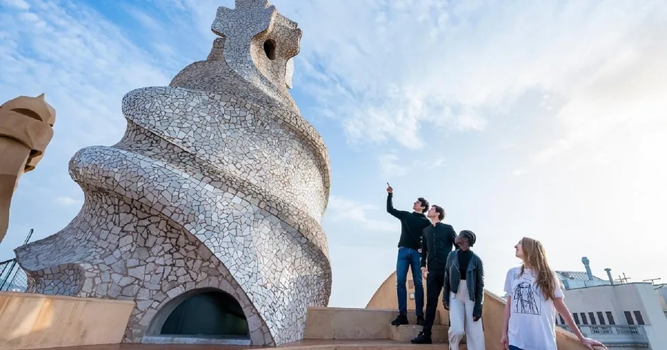 A spiral rooftop tower covered in white mosaic with visitors looking out over the city